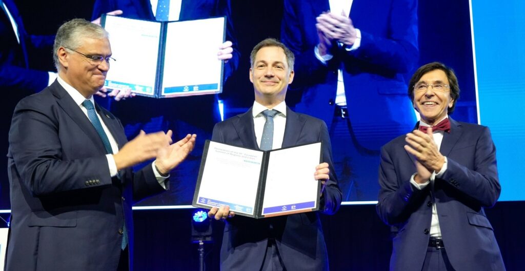 De gauche à droite, Vasco Alves Cordeiro, président du Comité européen des régions, Alexander De Croo, Premier ministre de la Belgique et Elio Di Rupo, ministre-président de la région Wallonne, brandissent la déclaration de Mons. Photo Comité européen des régions